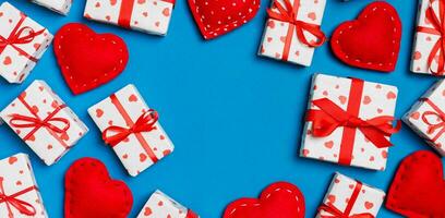 Top view of festive gift boxes and red textile hearts on colorful background with copy space. St Valentine's day concept photo