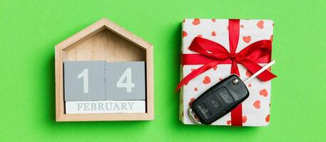 Top view of car key on a gift box with red hearts and festive calendar on colorful background. The fourteenth of february. Present for Valentine's Day concept photo