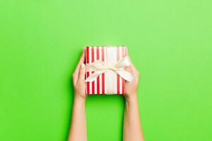 Top view of female hands holding christmas or other holiday handmade present box package in the palms, flat lay table background with copy space photo