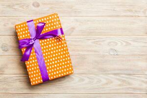 Beautiful gift box with a colored bow on the yellow wooden table. Top view banner with copy space for you design photo