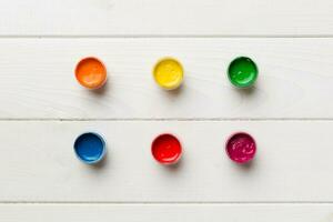 jars with gouache of different colors on Colored background. hobby painting. Top view with empty space. workplace for creativity. home teaching concept drawing photo