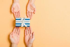 Top view of a man and a woman holding a gift box on colorful background. Love and relationship concept. Close up photo