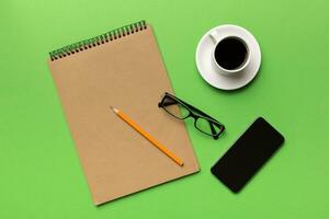Modern office desk table with notebook, smartphone and other supplies with cup of coffee. Blank notebook page for you design. Top view, flat lay photo