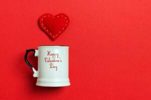 Holiday composition of red hearts falling out from a cup on colorful background. Top view of Saint Valentine's Day concept with copy space photo