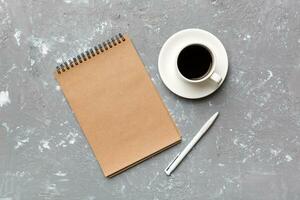 Modern office desk table with notebook and other supplies with cup of coffee. Blank notebook page for you design. Top view, flat lay photo