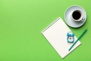 Modern office desk table with notebook and other supplies with cup of coffee. Blank notebook page for you design. Top view, flat lay photo