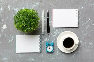 Modern office desk table with notebook and other supplies with cup of coffee. Blank notebook page for you design. Top view, flat lay photo