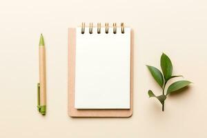 eco-friendly Empty notebook with pen and green leaf on Colored background for note photo