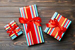 Beautiful gift box with a colored bow on the dark wooden table. Top view with copy space for you design. Christmas concept photo