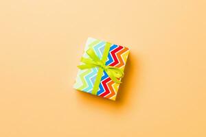 Top view Christmas present box with green bow on orange background with copy space photo