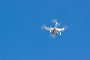 quadcopter zumbido es volador en el azul cielo. sin personal aéreo vehículo. remoto vídeo disparo desde un altura. moderno digital cámara foto