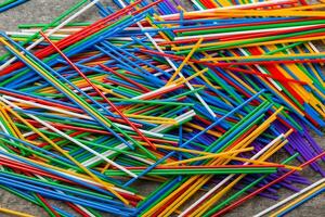 many multi-colored plastic tubes for cocktail on Colored background, top view photo