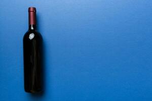 One Bottle of red wine on colored table. Flat lay, top view wth copy space photo