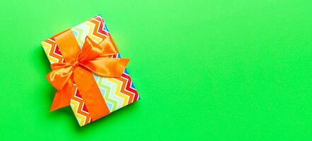 Top view Christmas present box with orange bow on green background with copy space photo