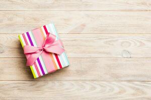 paper gift box with colored ribbon on orange wood background. top view with copy space Christmas holiday concept photo