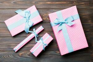 Beautiful gift box with a colored bow on the dark wooden table. Top view with copy space for you design. Christmas concept photo