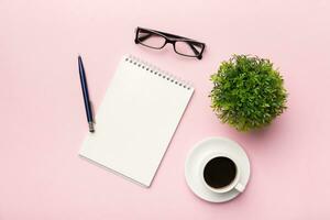 Modern office desk table with notebook and other supplies with cup of coffee. Blank notebook page for you design. Top view, flat lay photo