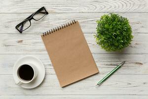 Modern office desk table with notebook and other supplies with cup of coffee. Blank notebook page for you design. Top view, flat lay photo
