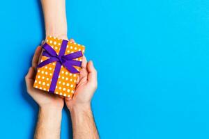 Top view of a woman and a man giving and receiving a present on colorful background. Love and relationship concept. Copy space photo