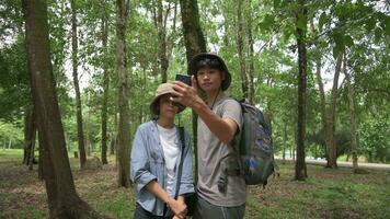 Due giovane adolescente Università studenti ricerca il direzione e Posizione di estate campo con mobile Telefono App mentre escursioni a piedi nel il foresta parco. video