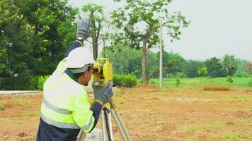 topógrafo ingeniero con equipo teodolito o total posicionamiento estación en el construcción sitio. video