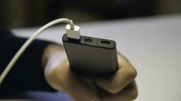 Close up of hand inserting a USB cable charger into portable power bank. Media. Close up of mans hand inserting a cable into charger. photo