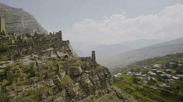 Ruins of ancient city on rocks on sunny day. Action. Stone city on rock in mountains. Historical stone town on rock above mountain valley photo