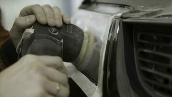 Close up for auto mechanic buffing and polishing car head. light. Art. Worker polishing the headlight of a car at automobile repair and renew service station, using a professional power buffer machine photo