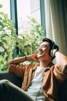 AI generated Asian mid adult men sitting near window with green house plants listening to music with headphones. photo