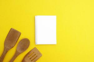 A set of bamboo dishes and blank notebook on a bright yellow background. photo