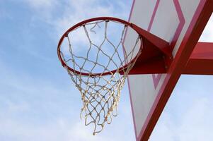 Basketball hoop with sky and clouds in uprisen angle view. photo