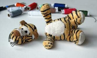 Plush tigger with a torn head. Sewing kit. photo