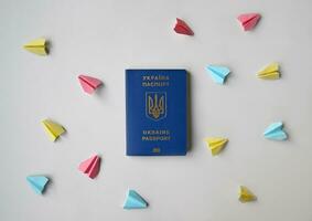 nuevo ucranio biométrico pasaporte y de colores papel aviones en un blanco antecedentes. foto