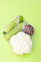 Ripe green zucchini, red onion and cauliflower in a string bag. photo