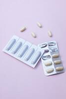 Gynecological medicines for women's health in form of suppository, capsules on pink background. photo