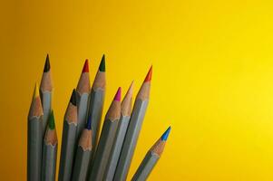 Many colorful pencils laying on yellow background. photo