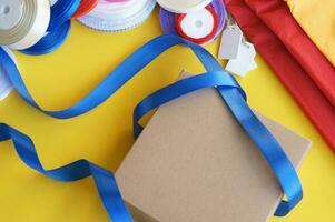 Gift box packaging on a yellow background. A lot of bright satin ribbons. photo