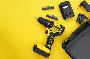 The yellow-black screwdriver on a yellow background, a set of bits. photo