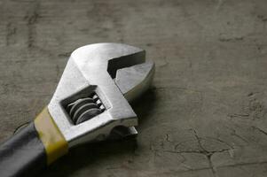 Adjustable wrench with yellow handle on the wood background photo