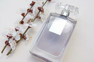 ligero belleza escritorio antecedentes con botella de hembra perfume y florecer rama cereza. foto