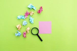 Top view photo of a magnifying glass and blank sticker on a green background.