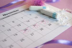 Menstrual tampons on menstruation period calendar with on lilac background. photo