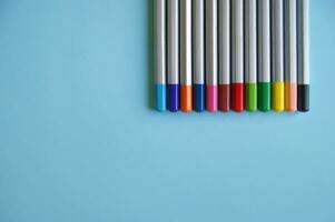 Many color pencils lies on light blue background photo