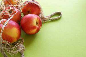 Red apple and string bag on a bright green background. photo