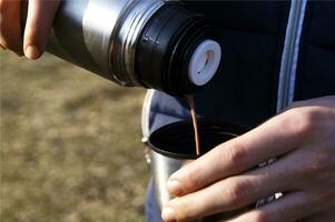 Man's hands pouring fresh hot cocoa from thermos to cup. photo