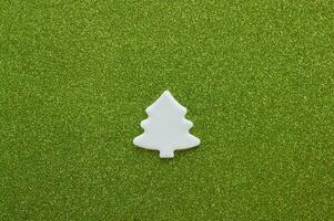 White carved christmas tree of mastic on green background. photo