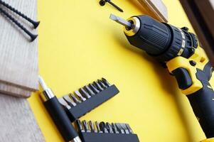 Yellow-black screwdriver on a yellow background, screws, a set of bits. photo