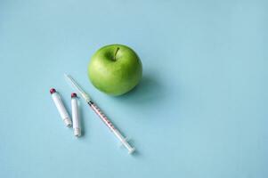 Green apple and syringe with GMO on a blue background. photo