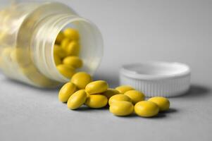 Inverted jar with yellow pills on a gray background photo