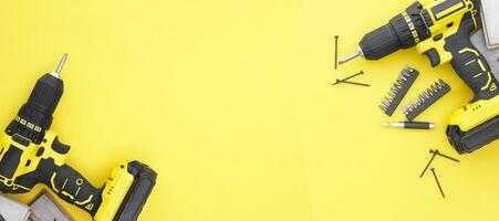 The yellow-black screwdriver on a yellow background, screws, a set of bits. photo